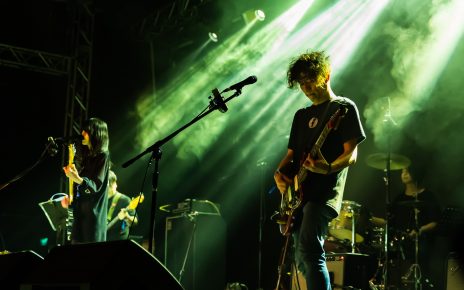 man in black crew neck t-shirt playing guitar on stage