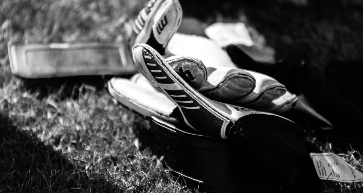 greyscale photo pair of gloves on grass field