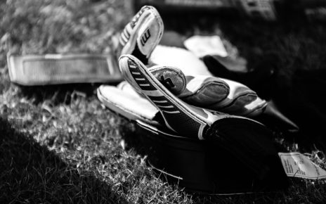 greyscale photo pair of gloves on grass field
