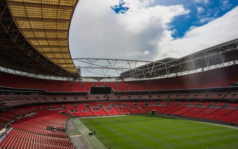 a large stadium with a green field and red seats